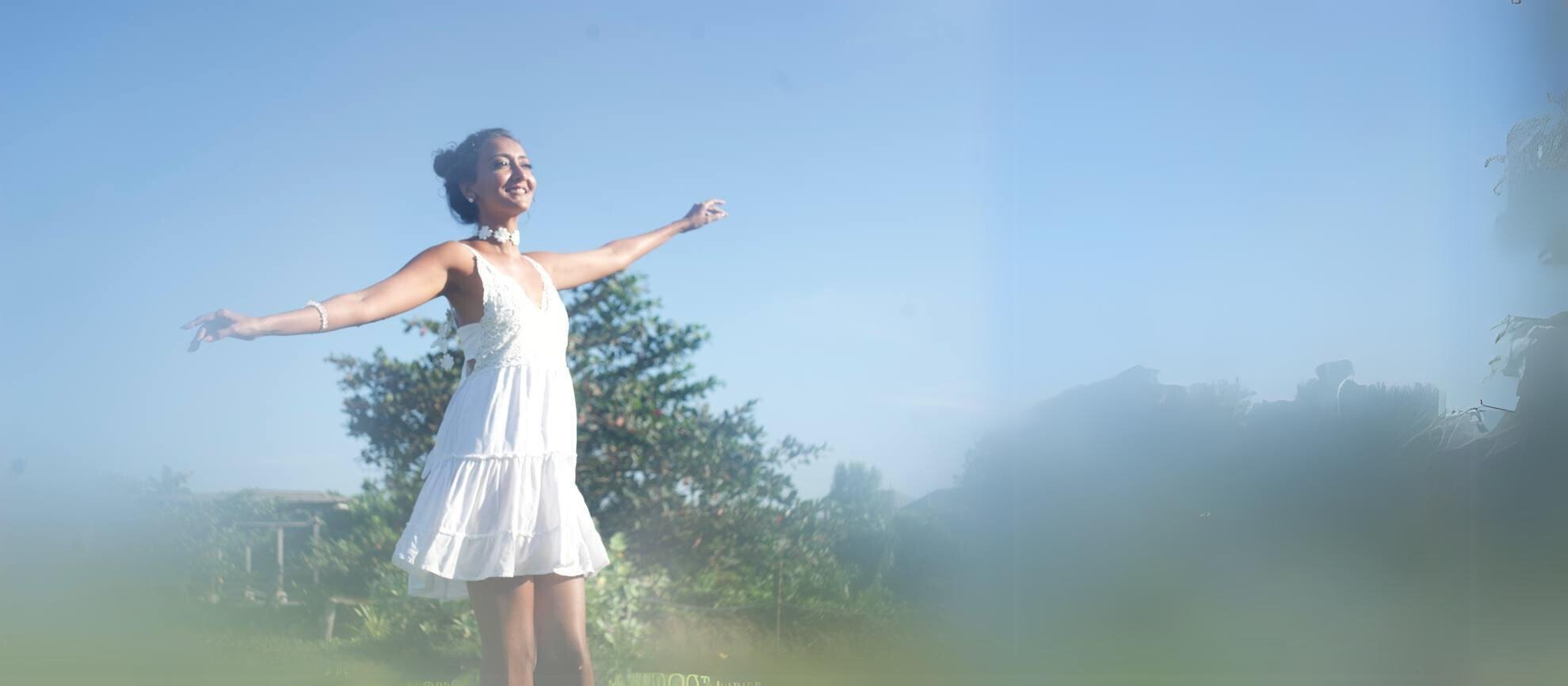 a person in a white dress with their arms outstretched symbolizing the freedom and power that Komal has learned to access and embody.